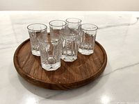 Six shot glasses on teak tray, full view