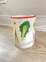 White ceramic cylinder jar with vegetable illustrations and red rim