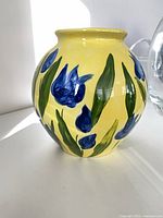 Round yellow clay vase with blue flowers and green leaves, approx 7 in high