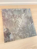 Top view of Taylor glass digital bathroom scale showing patterned surface and LCD screen