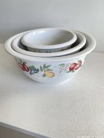 Nested set of three white ceramic bowls with fruit pattern