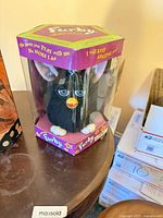 Front view of boxed black Furby toy