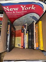 Box showing spines and covers of books including atlas, Weird NJ titles, Holy Bible and other paperbacks