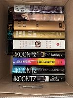 Top-down view of nine hardcover novels inside a box, spines visible for title and author identification