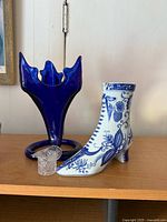 Cobalt blue vase, ceramic boot, clear glass hat on shelf
