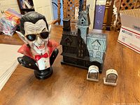 Dracula bust, haunted house model, tombstone shakers on table