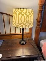 Full view of lamp on table, showing black base and patterned shade