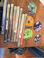Stack of seven PS2 game cases alongside five loose discs on tabletop