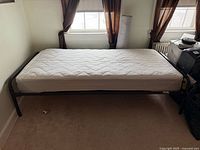 Mattress on metal frame against wall