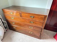 Front view of wooden dresser with five drawers, showing brass recessed handles
