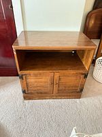 Front view of wood TV stand showing top, open shelf, and two-door cabinet