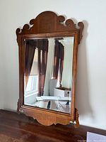 Front view of wood wall mirror hanging against wall