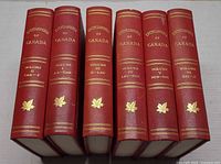 Spine view of all six red hardcovers with gilt titles and maple leaf motifs