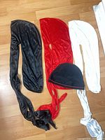 Three satin durags (black, red, white) and black skull cap laid out on floor