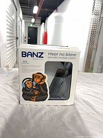 Front of retail box showing product name, age range, view of blue earmuffs inside