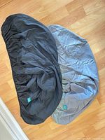 Two grey Biloban cushion covers laid flat showing elastic edges and brand tags