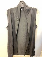 Front view of black sleeveless hooded tunic hanging