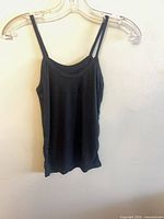Front view of black slim camisole on hanger showing thin straps and neckline