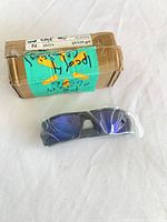 Sunglasses sealed in plastic sleeve beside small cardboard box