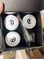 Open box showing three tins labeled Oak, Hickory, Apple wood chips, gold-tone stirring stick, sealed accessory