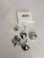 All four tea infusers, spare parts bag and packaging shown on white surface