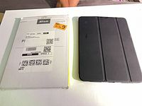 Front of retail sleeve beside closed black folio case