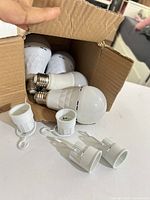 Box containing four LED bulbs and four socket adapters
