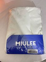 Front view of sealed MIULEE curtain package showing brand label and white sheer fabric inside