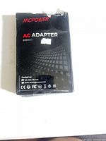 Front view of shrink-wrapped NicPower AC adapter retail box showing brand name and damage at top