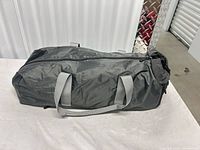 Full view of soft-sided charcoal gray cat carrier with light-gray handles and zipper top