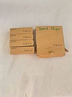 Front view of four small spark plug boxes and outer box