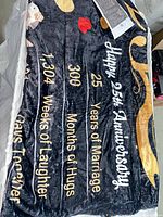 Partially unfolded plush throw blanket showing printed 25th anniversary design and text
