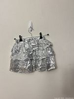 Front view of silver sequin tiered mini skirt hanging