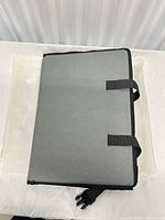 Mat folded showing grey outer surface and two web loops