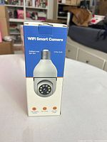 Front of retail box showing WiFi Smart Camera bulb design and feature icons