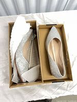 Top view of both silver glitter flats inside shoebox with tissue paper