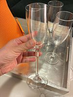 Hand holding one flute with other three in background, clear view of bowl and stem