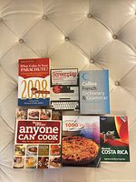 Six books laid out on cushioned surface