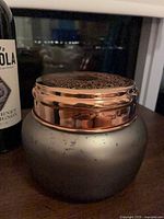 Jar candle with lid on, showing metallic grey jar and copper lid