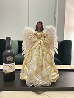 Front view of angel tree topper beside wine bottle for scale