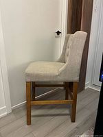 Side view of upholstered stool showing profile and wood legs