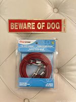 Packaged PetStore red tie-out cable with included Beware of Dog sticker