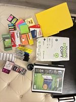 Full assortment laid out showing paper ream, folders, binder, writing instruments, clips, labels