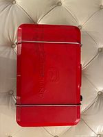 Closed red Outbound camp stove top view with embossed logo and wire lid latches