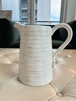 Front view of white ribbed ceramic jug with spout and handle