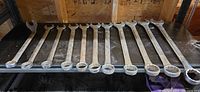 All twelve large combination wrenches laid out on shelf