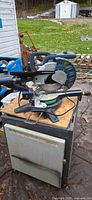 Left side view of blue compound mitre saw on work surface
