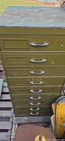 Tall green metal cabinet with eight drawers on a pallet