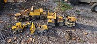 All six Tonka trucks on gravel surface