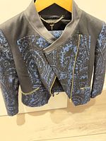 Front view of cropped jacket showing paisley fabric, gold zippers, chain hanger